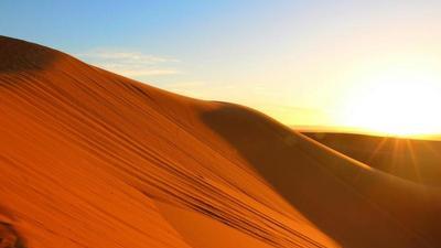 sun setting on a hill of red sand in the Sahara Desert