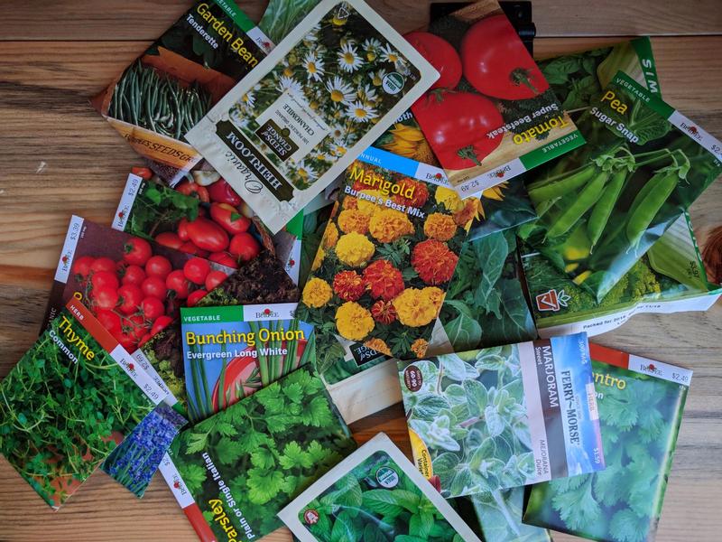 a pile of packets of seeds for flowers, herbs, and vegetables