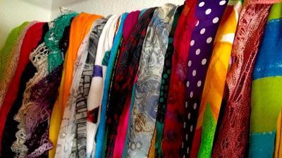 A row of colorful scarves hanging in a closet