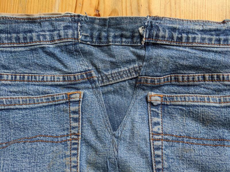a section of blue jean fabric shaped like a triangle connecting the flat waistbands of two old pairs of jeans