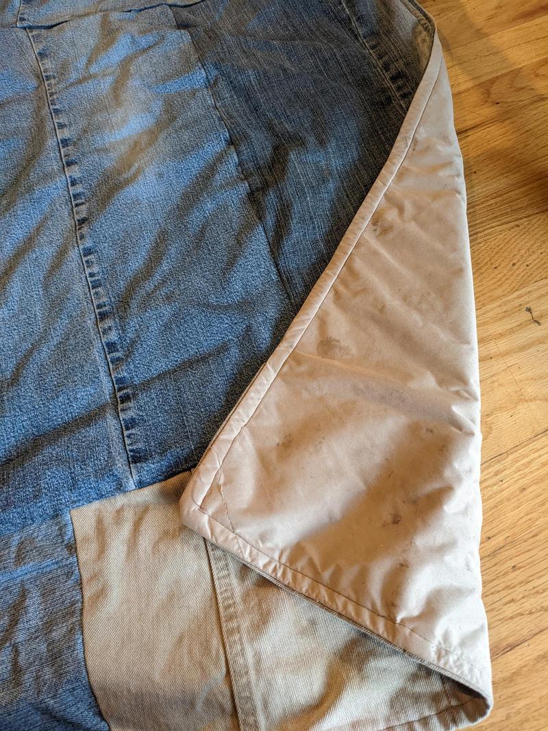a section of a picnic blanket made of old blue jeans, with a corner flipped to show that the backside is made from shower curtain liner