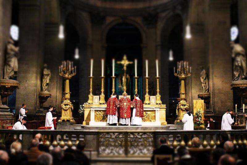 Priests in red and gold celebrate a traditional Latin Mass