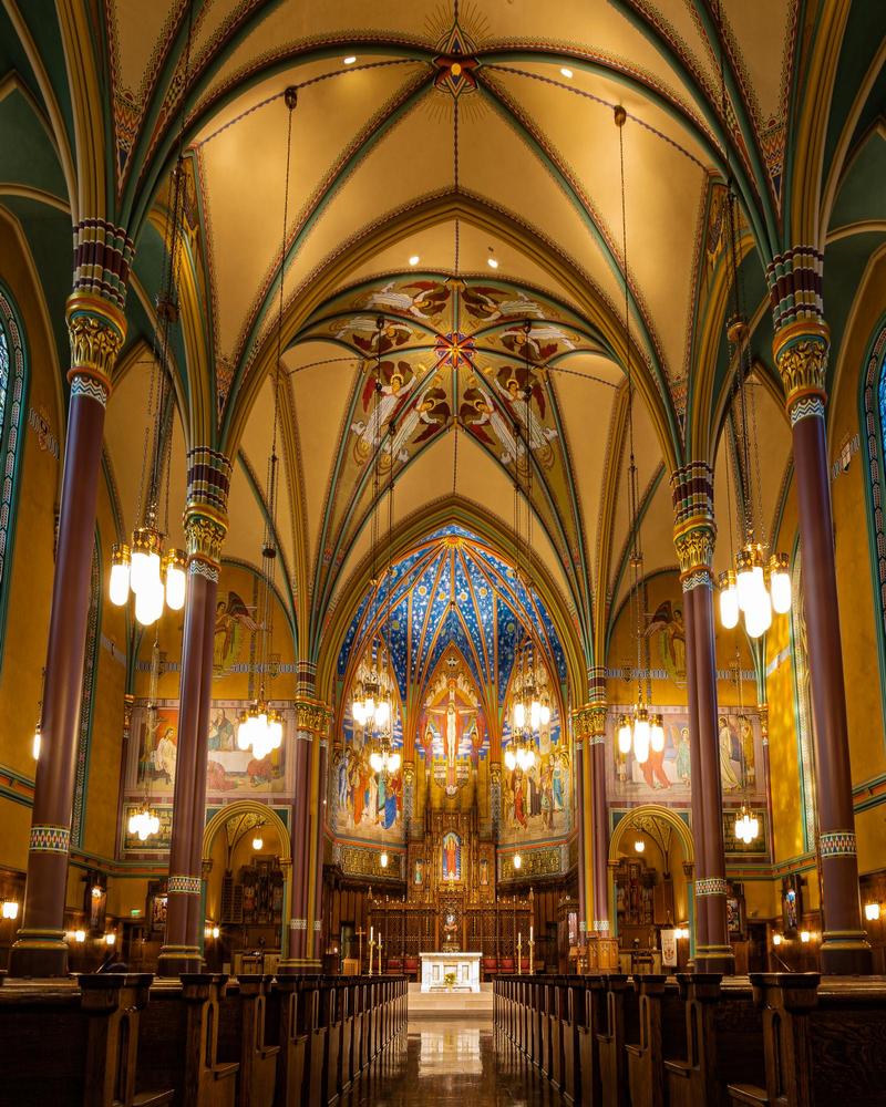 inside of the Cathedral of the Madeleine in Salt Lake City, with beautiful arches, paintings, and gold tim